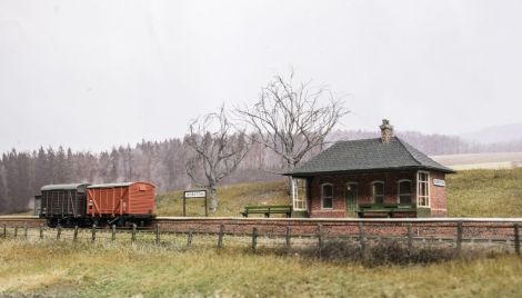 Das neue Ensamble aus Geb&auml;ude mit Windschutz, B&auml;nken und Bahnhofsschildern.